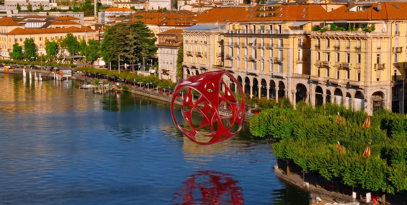 The Kaleidos Sphere Red sculpture hovering above Lake Lugano